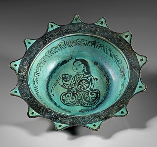Los 715: Glasierte sternförmige Schale aus grauem Ton mit türkisgrüner Grundierung und schwarzer Bemalung. Islamisch, 12./13. Jh. Dm. 23,5 cm. Taxe: 1.000 EUR.