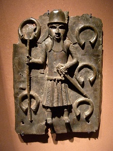 Beninbronze: Portugiesischer Sklavenhändler umgeben von Manillen; aus diesen Bronzearmbändern wurden die prachtvollen Beninbronzen gefertigt. Foto: UK.